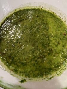 Picture of a cup filled with chimichurri sauce.