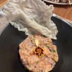 Picture of Salmon Tartare plated with a fried rice paper garnish on a black plate.