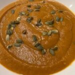 Picture of a bowl of creamy butternut squash soup topped with pumpkin seeds.