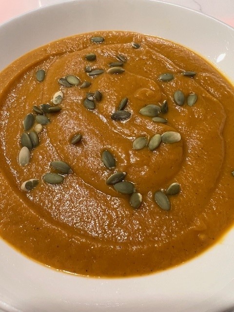 Picture of a bowl of creamy butternut squash soup topped with pumpkin seeds.