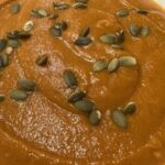 Picture of butternut squash soup topped with pumpkin seeds.