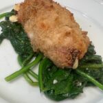 Picture of Chicken Cordon Blue plated on top of reduced spinach and garlic.