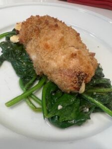 Picture of Chicken Cordon Blue plated on top of reduced spinach and garlic.