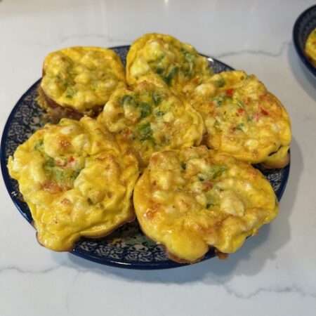 Picture of vegetable egg muffins on a blue plate on a white countertop.