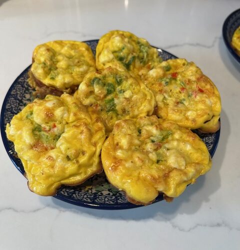 Picture of vegetable egg muffins on a blue plate on a white countertop.