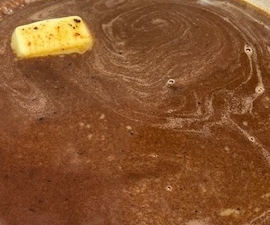 Picture of red wine steak sauce in a skillet pan with butter meting to the side.