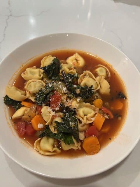 Picture of a white bowl filled with Tortellini Vegetable Soup.