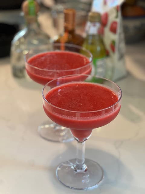 Picture of two strawberry margaritas in glasses on a counter.