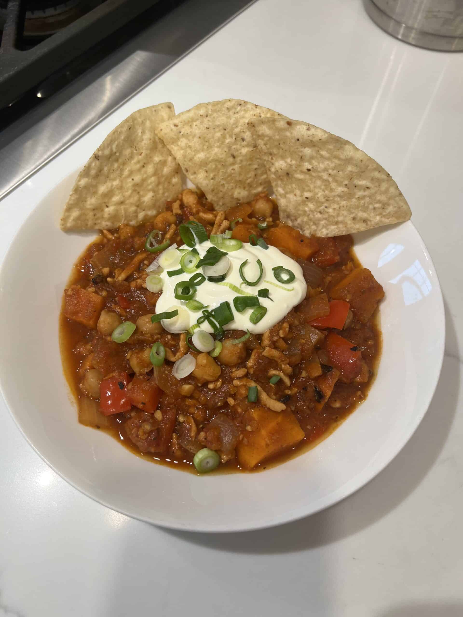 Picture of a bowl of Instant Pot Turkey Chili topped with sour cream and green onions and garnished with tortilla chips.